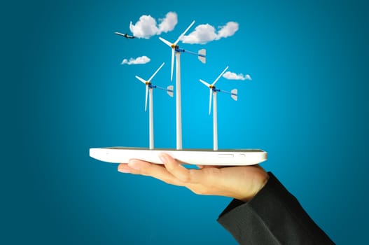 female hand holding a tablet touch computer gadget present wind turbine power generator 