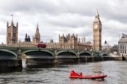 Houses of the British parliament and river Thames with red motor boat