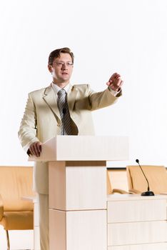 male speaker stands behind a podium on the stage and looking into the hall