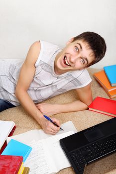 Cheerful Teenager doing Homework on the Sofa at the Home