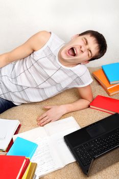 Tired Teenager Yawning on the Sofa with the Books at the Home