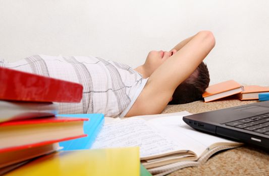 Tired Teenager sleeping on the Sofa with the Books