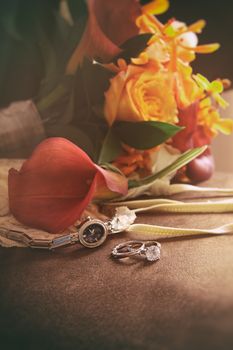 Wedding rings, watch and bouquet on chair