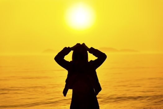 Silhouette of woman thinking on the beach at sunset