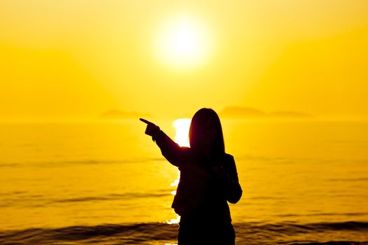 The silhouette of woman pointing at beach