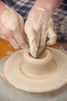 Hands of a potter, creating an earthen jar on the circle