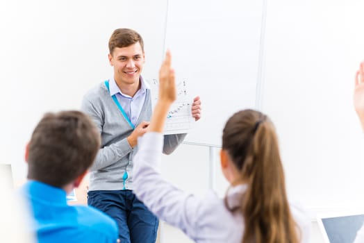 young teacher man talking with students in the classroom