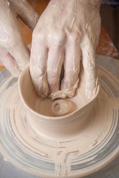 Hands of a potter, creating an earthen jar on the circle