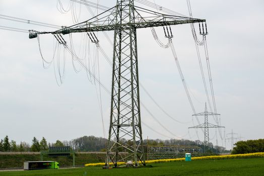 GUENZBURG, GERMANY - April 19, 2014: Construction works on high voltage power pole on April 19, 2014 near Guenzburg, Germany. The extended power lines are necessary due to increased power consumption by Legoland and other companies settling at Guenzburg. Since the power lines cross the Autobahn (highway), complex safety measures are in place.