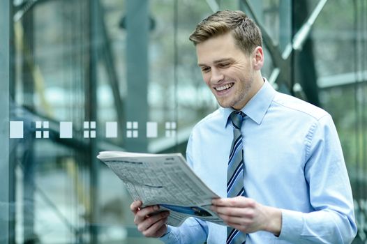 Young businessman reading newspaper at outdoors