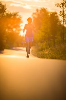 Young woman running outdoors on a lovely sunny summer evening (shallow DOF; color toned image)