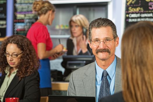 Handsome cheerful businessman talking sitting in cafeteria