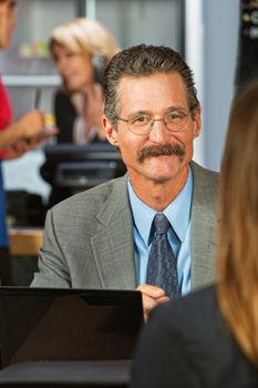 Cheerful businessman with eyeglasses and mustache with woman in cafe