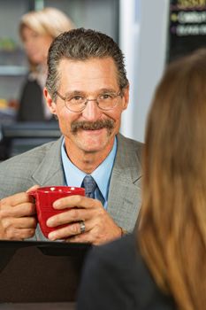 Happy businessman with coffee talking with woman