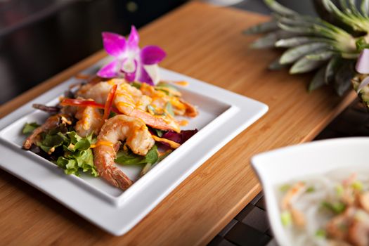 Thai shrimp dish presented on a white square dish.  Shallow depth of field.