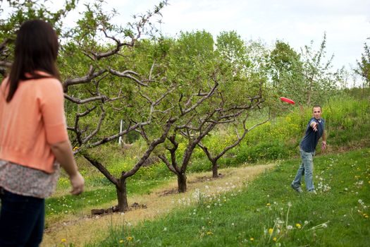 A couple plays with a toy disc together outdoors.