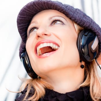 Blonde caucasian girl listening to the music with a pair of headphones