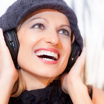 Blonde caucasian girl listening to the music with a pair of headphones