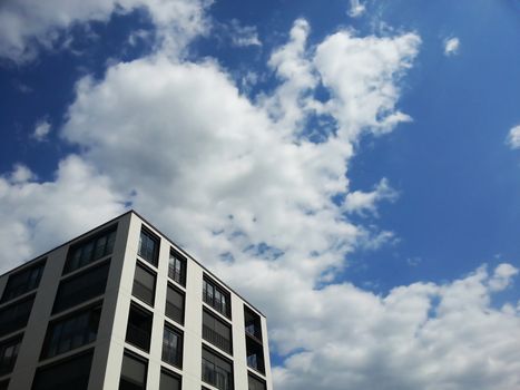 Modern white, gray and black building with moving sky in the background.