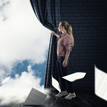 image of a young woman pushes the curtain looking at clouds