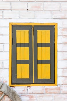 yellow wooden window on a brick wall.