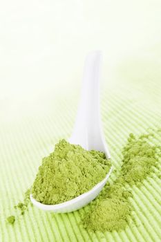 Detox. Wheatgrass powder on white spoon on green background. Alternative medicine. 