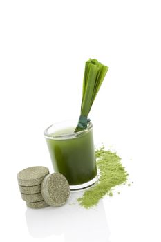 Green food supplement. Spirulina, chlorella and wheatgrass. Effervescent pills, wheatgrass blades, green juice and ground powder isolated on white background. Healthy lifestyle.