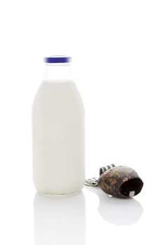 Milk in glass bottle with traditional cowbell isolated on white background with copy space. Traditional milk drinking.