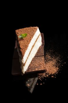 Tiramisu dessert on chocolate bar isolated on black background. Italian sweet dessert concept.