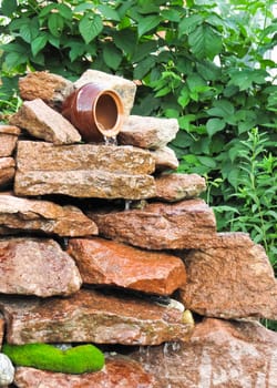 small waterfall of stones and a pot in the garden