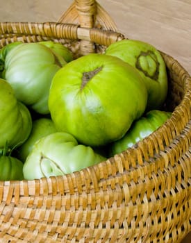 green tomatoes lie in a wicker basket