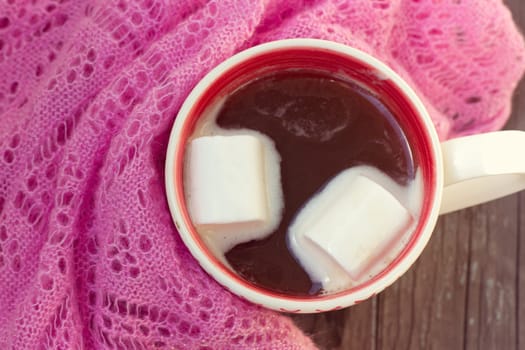 A rich cup of hot chocolate wrapped in a cozy winter scarf