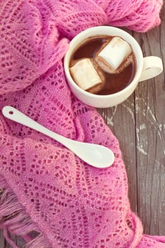 A rich cup of hot chocolate wrapped in a cozy winter scarf