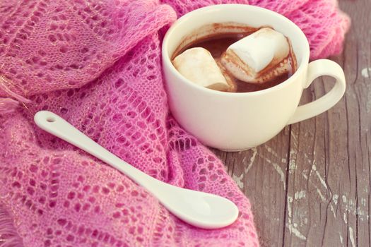 A rich cup of hot chocolate wrapped in a cozy winter scarf