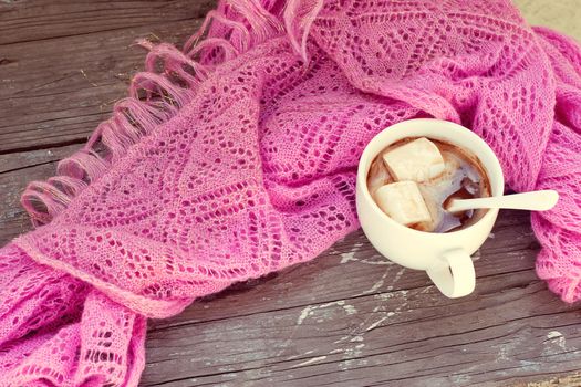 A rich cup of hot chocolate wrapped in a cozy winter scarf