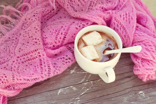 A rich cup of hot chocolate wrapped in a cozy winter scarf