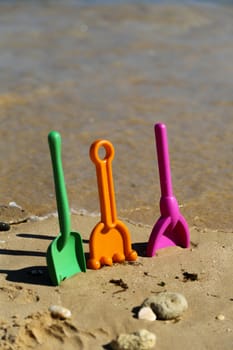 Plastic beach shovels in sand on a beach.