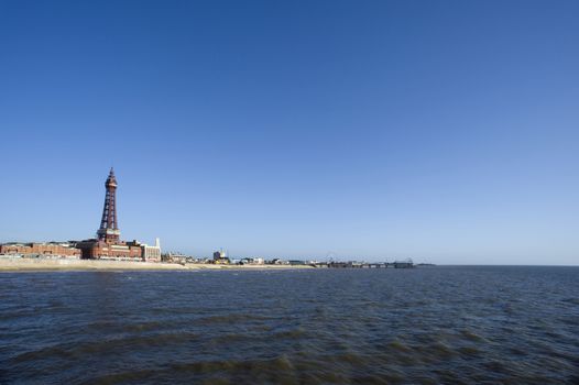 View of Blackpool seafront from the ocean showing the sandy beach dominated by the tall Victorian Blackpool tower at this popular Lancashire resort on a clear blue sunny day