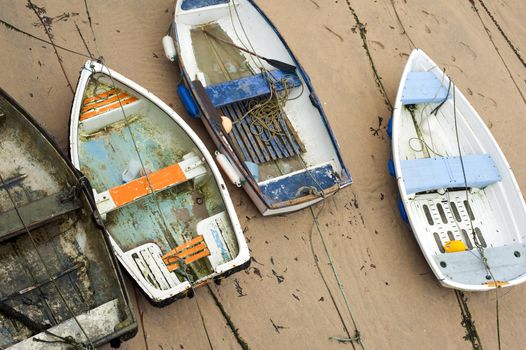 Small wooden boats beached high and dry on the sand by the retreating tide in St Ives harbour in Cornwall a popular fishing village and tourist resort