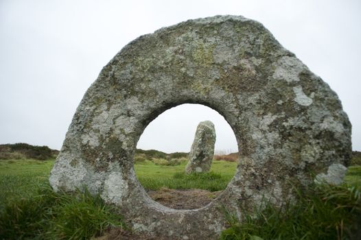 View through the circular hole in the centre of the round stone at Men-an-tol, Cornwall, a prehistoric Neolithic arrangement of granite megaliths near Morvah