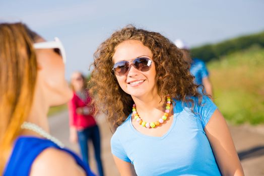 portrait of a stylish young woman on the background of young merry friends, spending time with friends