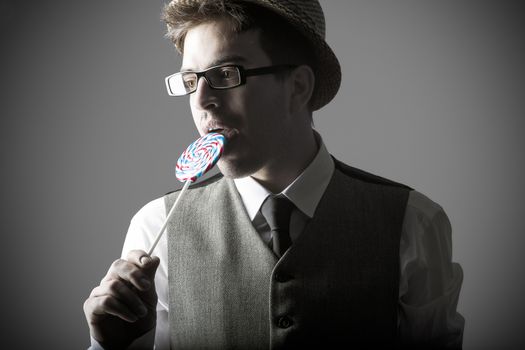 Portrait of stylish young man eating lollipops against grey background