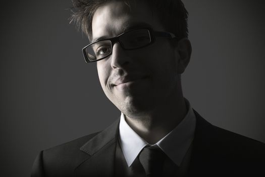 Portrait of smart young business man against grey background