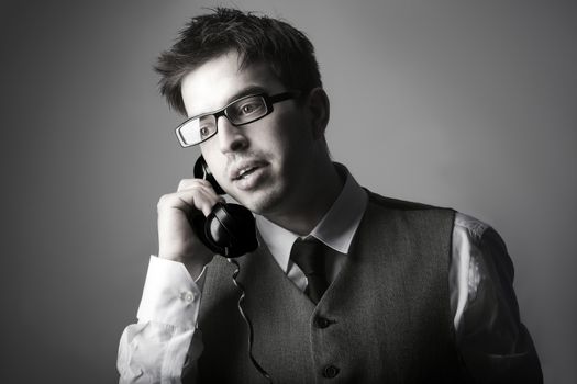 Young smart business man talking on the phone against grey background