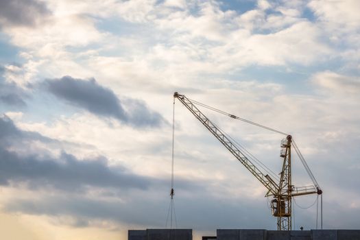 Construction crane on cloudy sky background