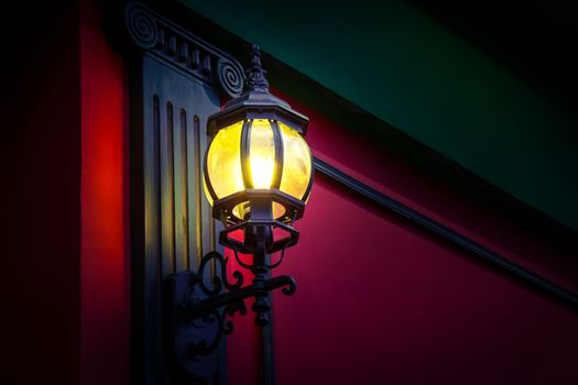 Vintage street lamp at the evening on red wall background