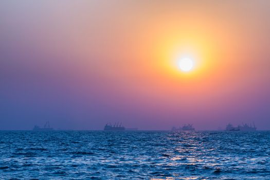 Scenic view of beautiful sunset above the Arabian sea. Cargo ship on the background
