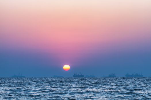 Scenic view of beautiful sunset above the Arabian sea. Cargo ship on the background