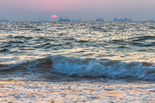 Scenic view of beautiful sunset above the Arabian sea. Cargo ship on the background