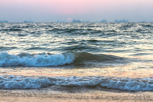 Scenic view of beautiful sunset above the Arabian sea. Cargo ship on the background